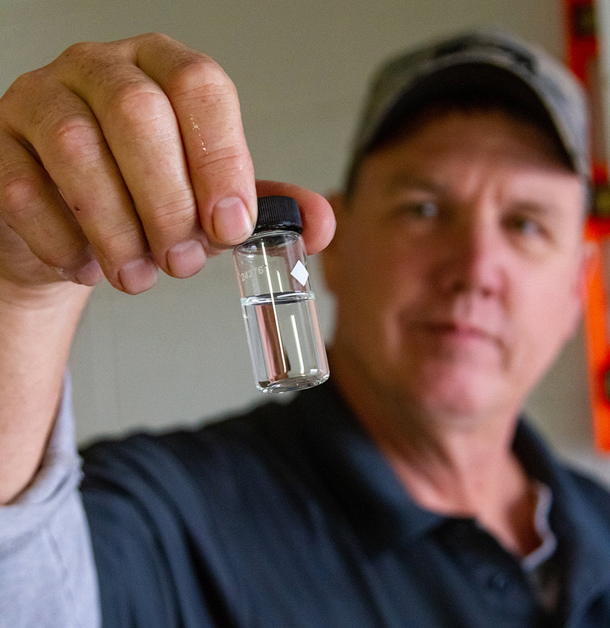 Man inspecting water vial for clarity